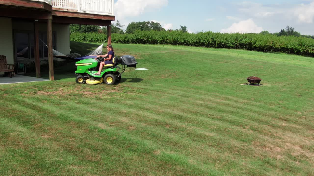 트랙터 커터에 잔디를 깎고 젊은 히스패닉 여자