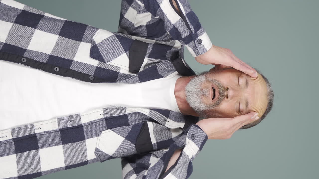 video vertical de un anciano con dolor de cabeza.