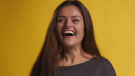 retrato de estudio de una mujer emocionada celebrando buenas noticias ganando dinero contra un fondo amarillo