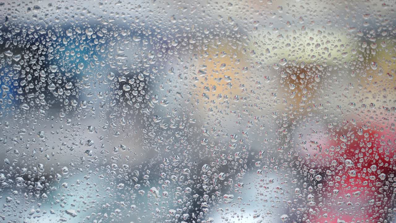 superficie húmeda de la ventana después de una fuerte lluvia, gotas en el vidrio de la ventanilla en el fondo borroso del tráfico callejero nublado. toma cinematográfica de gotas de lluvia, patrón de papel tapiz con espacio de copia