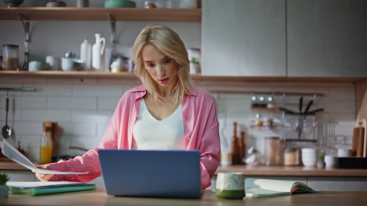 Blonde Frau, die Unterlagen prüft und in der Küche arbeitet, Nahaufnahme. Dame bei der Papierarbeit