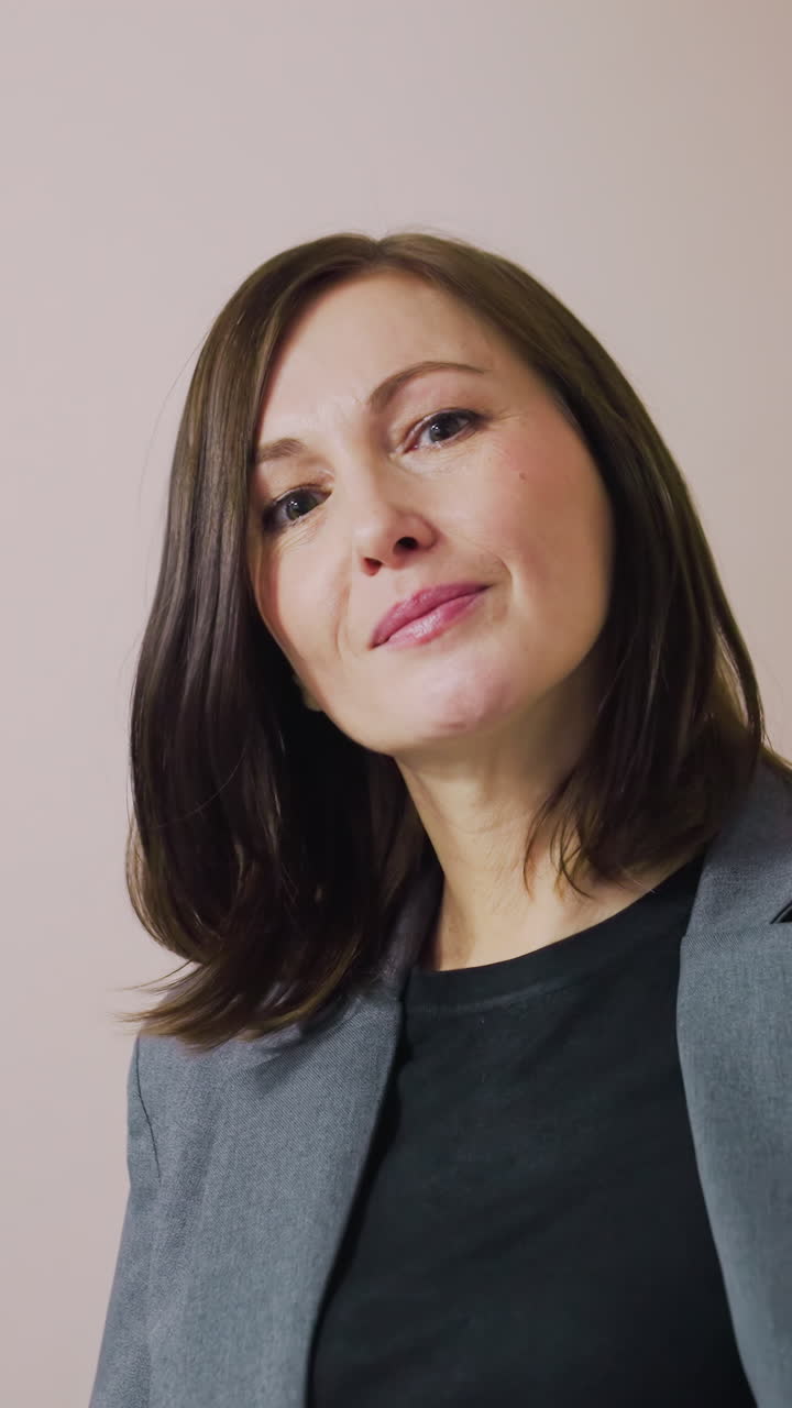Businesswoman smiling confidently while holding bag in office corridor, modern workspace with neutral colors, professional woman in business attire looking at camera