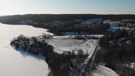 sobrevuelo aéreo hermoso paisaje invernal con campos agrícolas cubiertos de nieve y árboles forestales en suecia