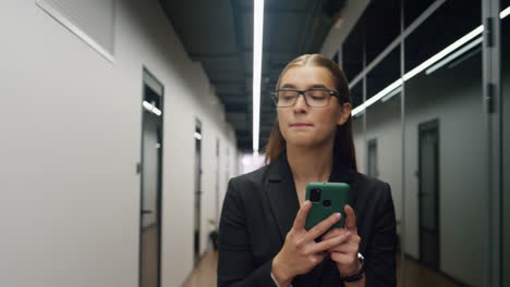 office girl typing smartphone walk on lunch break. focused employee go corridor