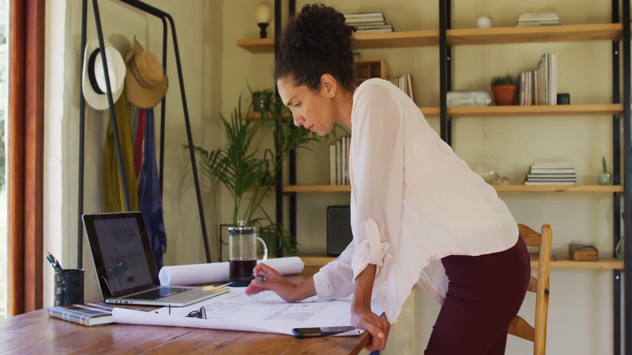 Caucasian woman standing by desk, working from home