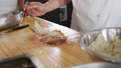 cocinera caucásica enseñando a un grupo diverso preparando platos y sonriendo