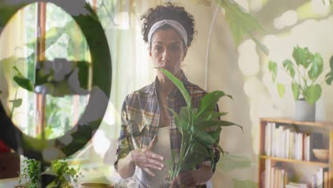 animation of plants over biracial woman potting plant and vlogging