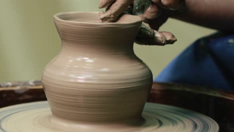 las manos de la mujer en la rueda de la cerámica. el artesano el artista da forma a la olla