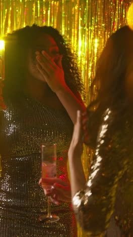 Vertical-Video-Of-Two-Women-In-Nightclub-Or-Bar-Dancing-Drinking-Alcohol-With-Sparkling-Lights-In-Background-4