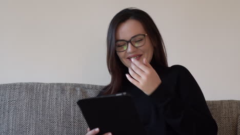 Portrait-of-a-young-woman-laughing-while-watching-something-funny-on-the-tablet