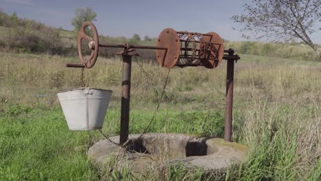 un viejo pozo de agua en una finca rural, un pozo abandonado en medio de hierba verde y árboles.