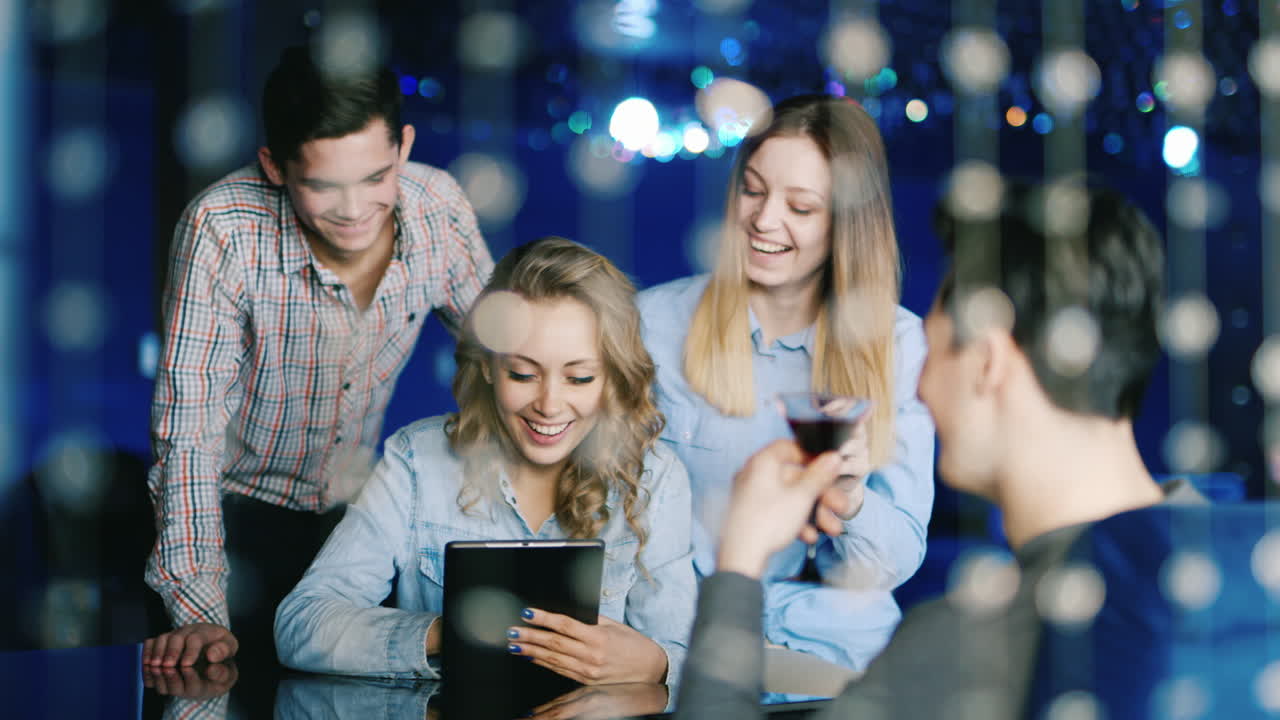 un grupo de jóvenes alegres miran la pantalla de la tableta