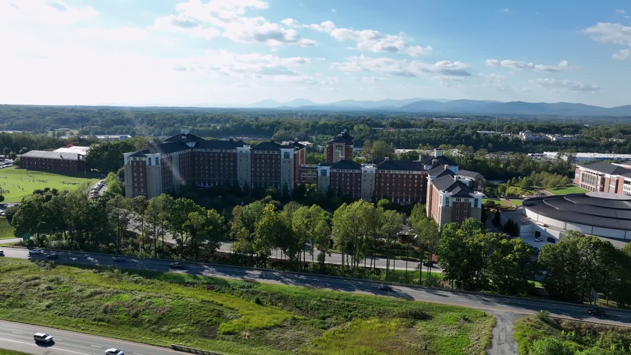 Aerial view of residential commons apartment of liberty university with traffic on interstate road in Lynchburg, Virginia. Wide shot. Sunny summer day in USA. Liberty arena of woman basketball