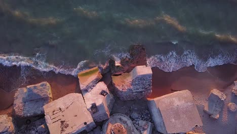 aerial birdseye view of abandoned seaside fortification buildings at karosta northern forts on the beach of baltic sea in liepaja, latvia, calm sea, golden hour, wide angle point of view drone shot