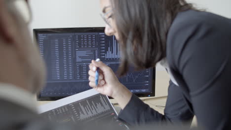 serious female broker explaining financial report to businessman