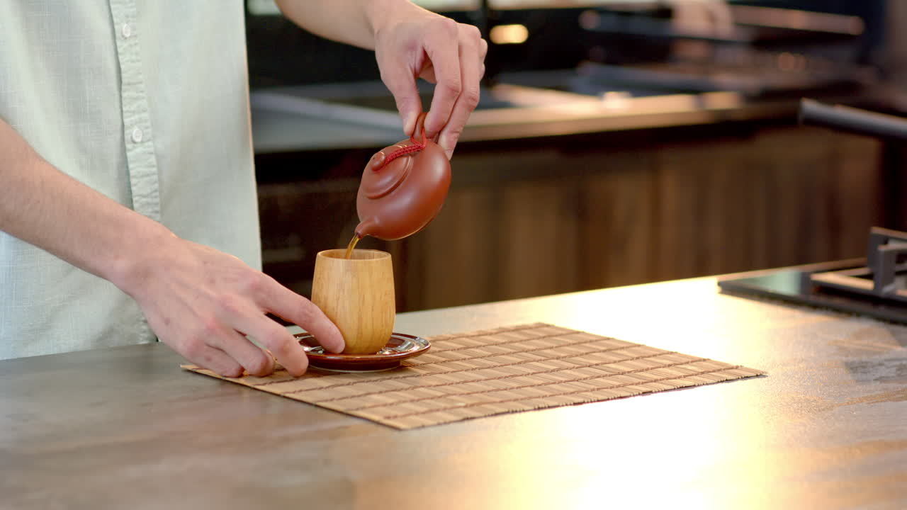 Pouring tea into wooden cup on kitchen counter, creating cozy holiday atmosphere, copy space
