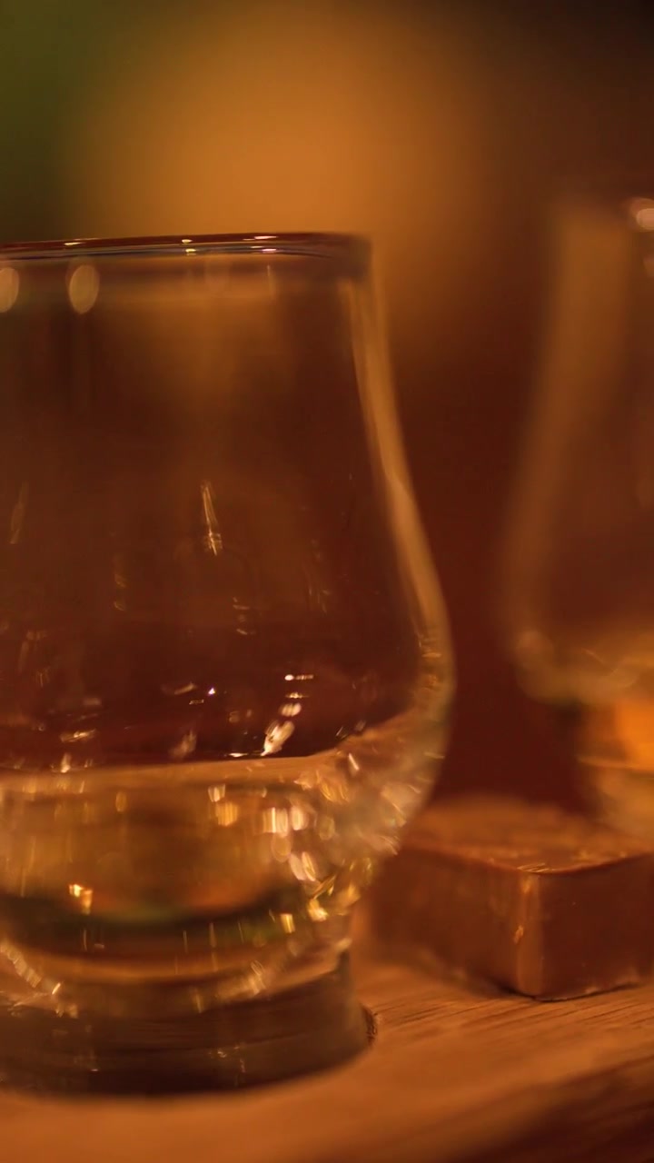 Persona che prende un bicchiere di whisky in un bar in penombra