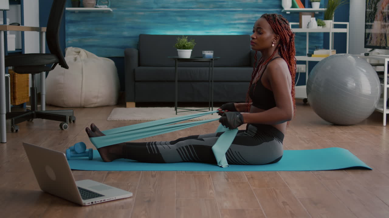 Athetic black woman in sportswear watching aerobic online sport workout