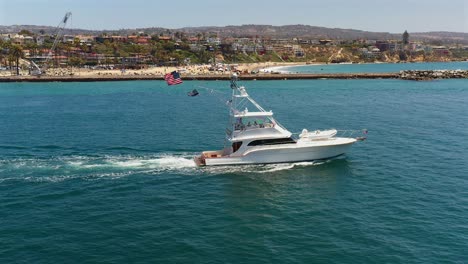 Aerial-side-view-of-a-large-fishing-boat-flying-American-flags-in-Newport-Beach,-California