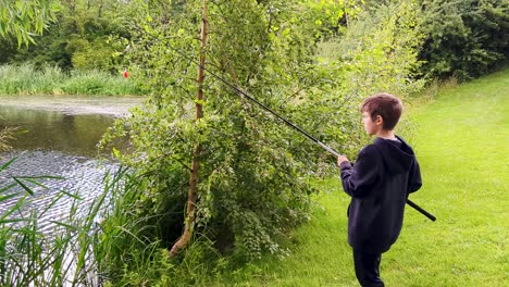 4k 60fps young boy fishing in a small pond in denmark, boy coarse fishing roach - panoramic shot