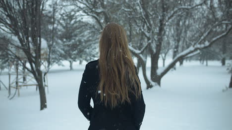 Woman-walking-outside-in-slow-motion-winter-snow-as-snowflakes-fall-in-cinematic-slow-motion