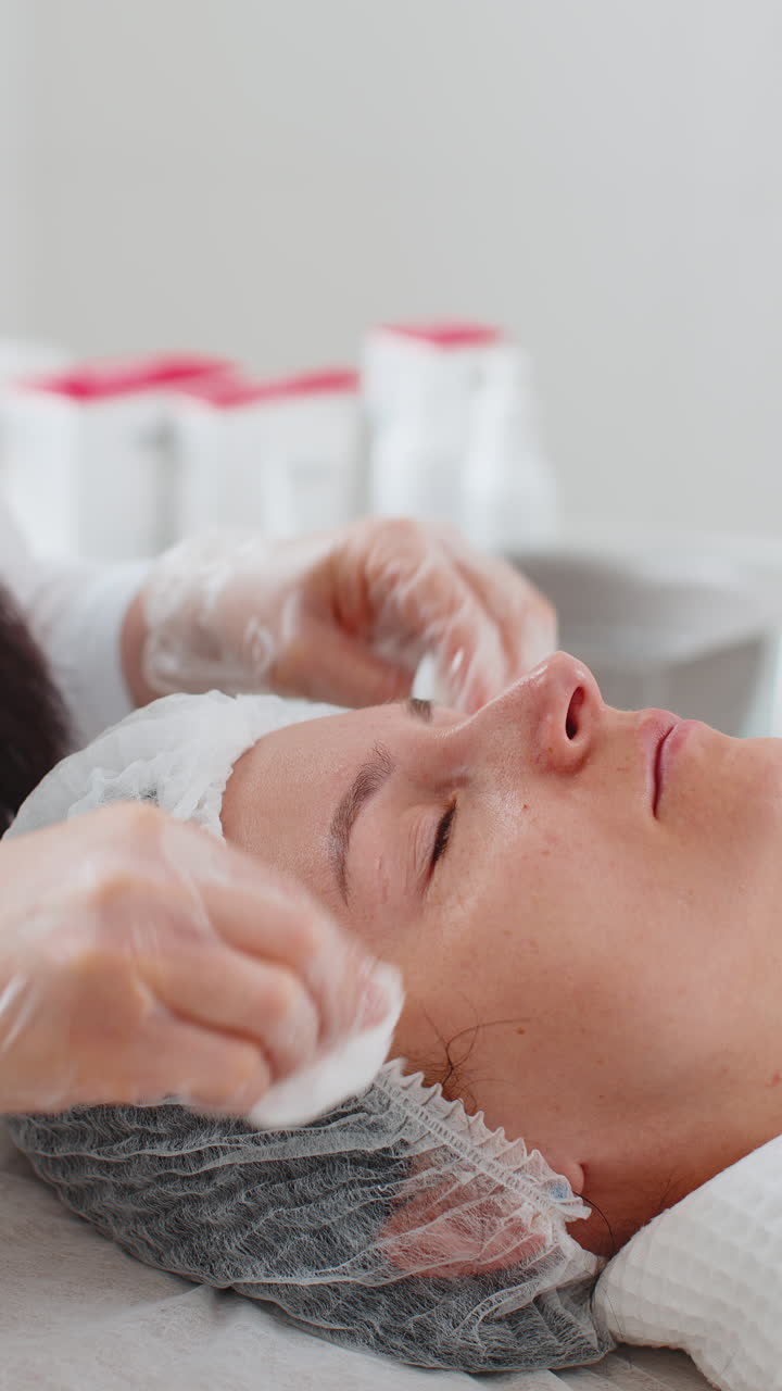 cosmetólogo médico limpia la cara y los ojos de la mujer procedimiento de limpieza con toallitas de algodón en la clínica de belleza