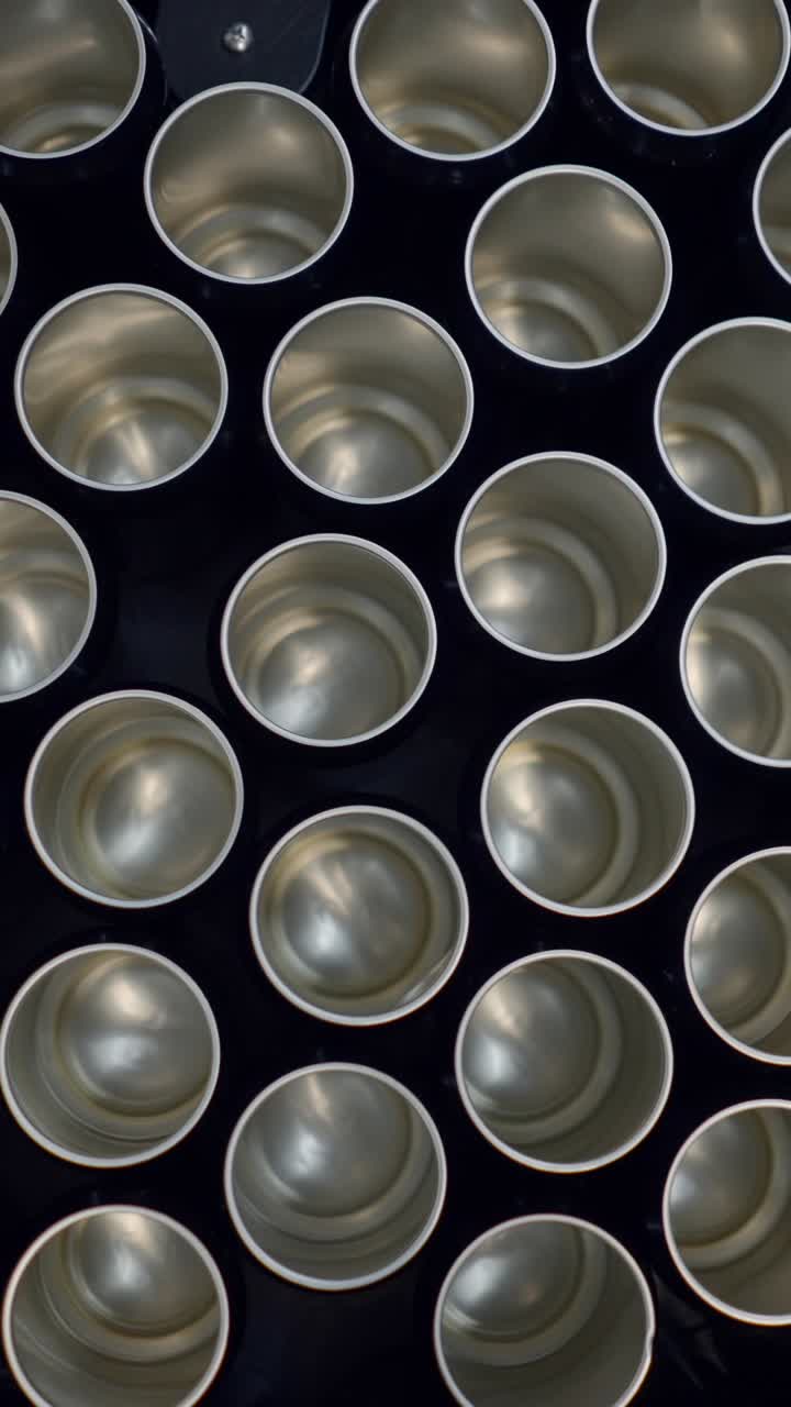 A grid of empty metal cans on a dark surface