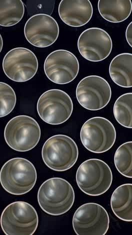 a grid of empty metal cans on a dark surface