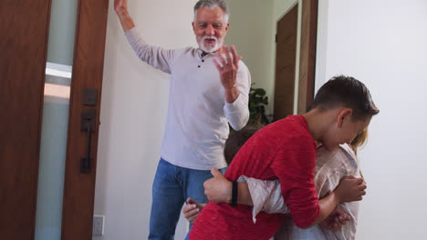 abuelos saludando a la familia en la puerta de entrada cuando vienen a visitar