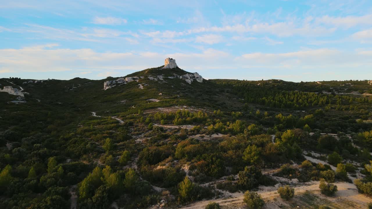 Aerial establishing shot of a large rock formation surrounded by vineyards