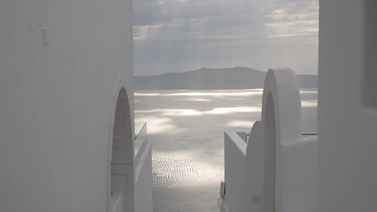 Porta ad arco imbiancata a calce che incornicia una scintillante vista mare della caldera, Santorini, Grecia.