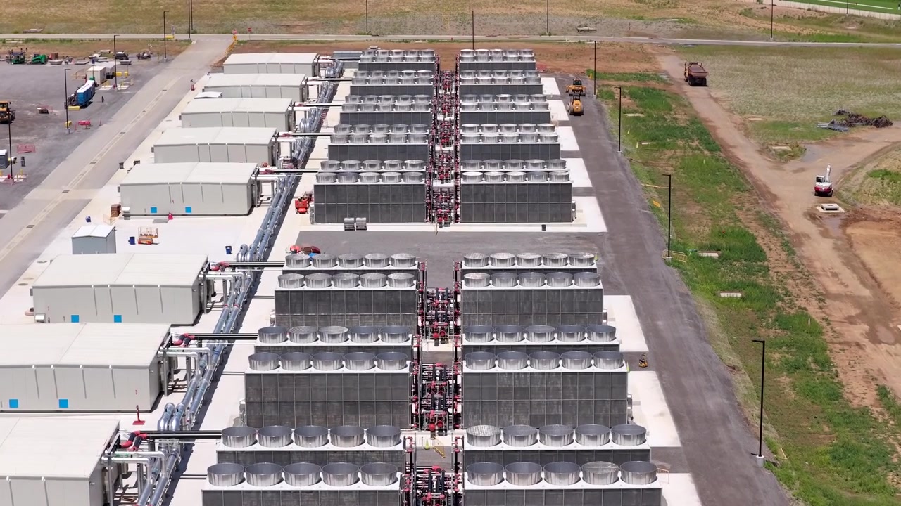 Grandi refrigeratori a secco raffreddati ad aria e unità di raffreddamento a fluido in un data center ad alta tecnologia di giorno, che mostrano la scala industriale e le moderne infrastrutture, con un sorvolo aereo in picchiata