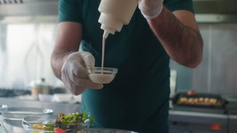 The-cook-fills-the-small-bowl-with-sauce-and-salad-dressing