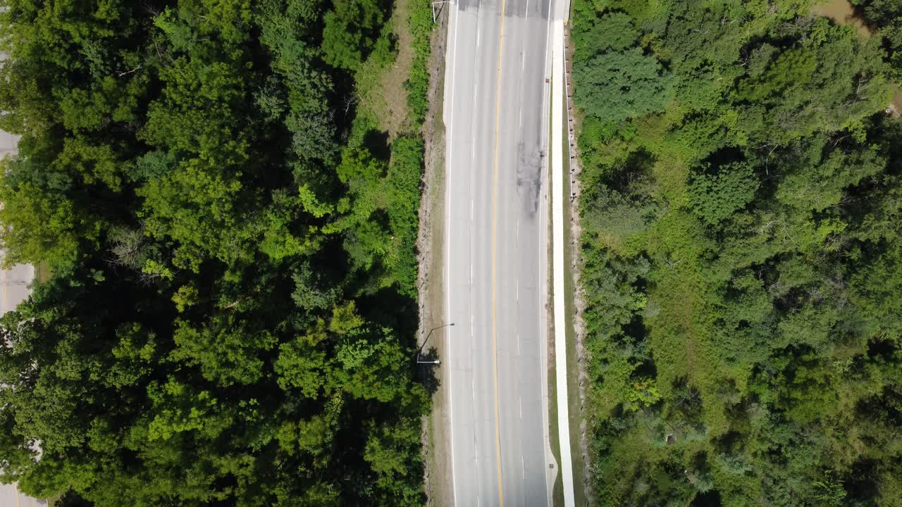 Bird eye view of a perfectly symmetrical highway hidden within forested area in Ontario canada