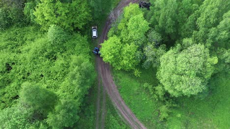 tractor local preparándose para sacar un vehículo roto de la pista de carreras forestal, vista aérea