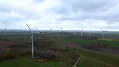 Toma-Aérea-De-Múltiples-Turbinas-Eólicas-Giratorias-Para-La-Producción-De-Energía-Eléctrica-Renovable-En-Una-Amplia-Zona-Rural-En-Un-Día-Nublado-En-4k