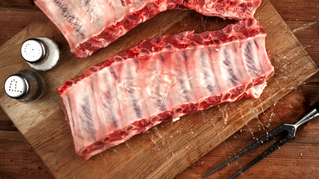 Fresh Raw Pork Ribs on a Wooden Cutting Board with Splashing Water