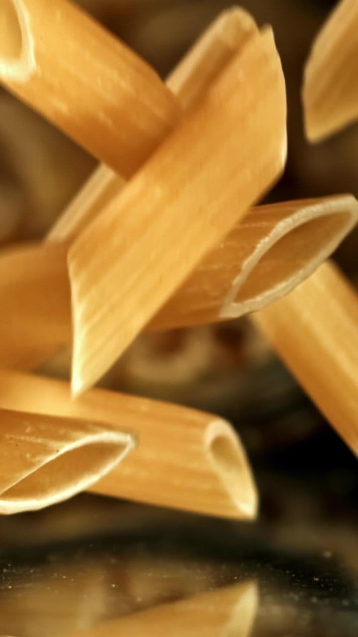 Pezzi di pasta penne cruda che cadono al rallentatore.