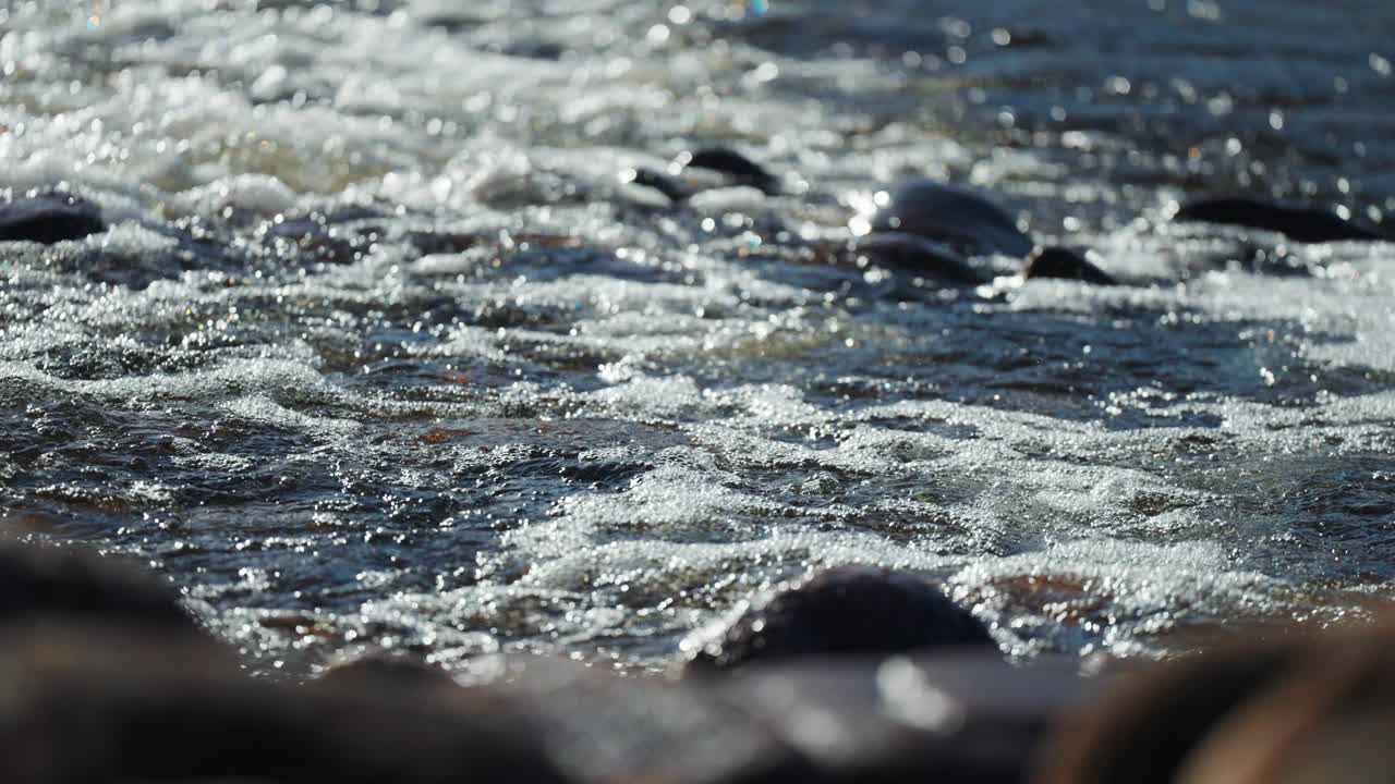 Onde si infrangono sulla spiaggia di ciottoli in un primo piano