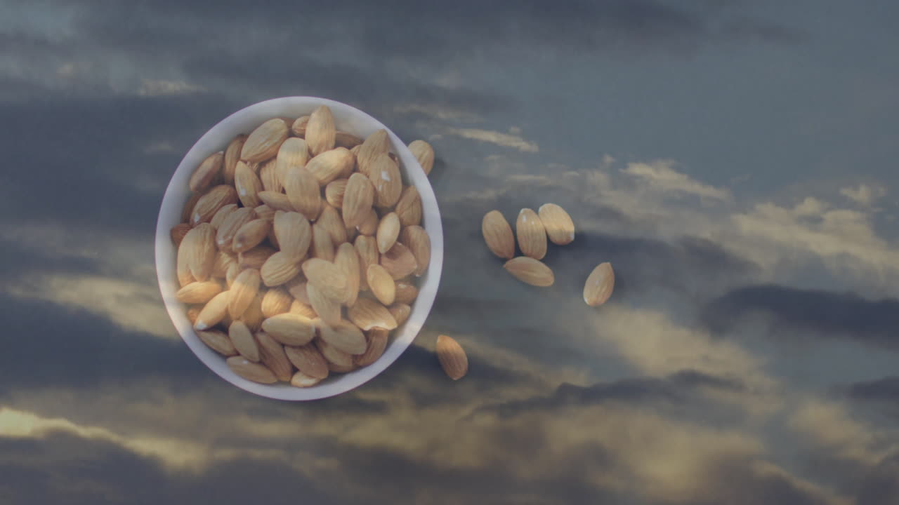 Creating surreal effect, bowl of almonds floating against cloudy sky background