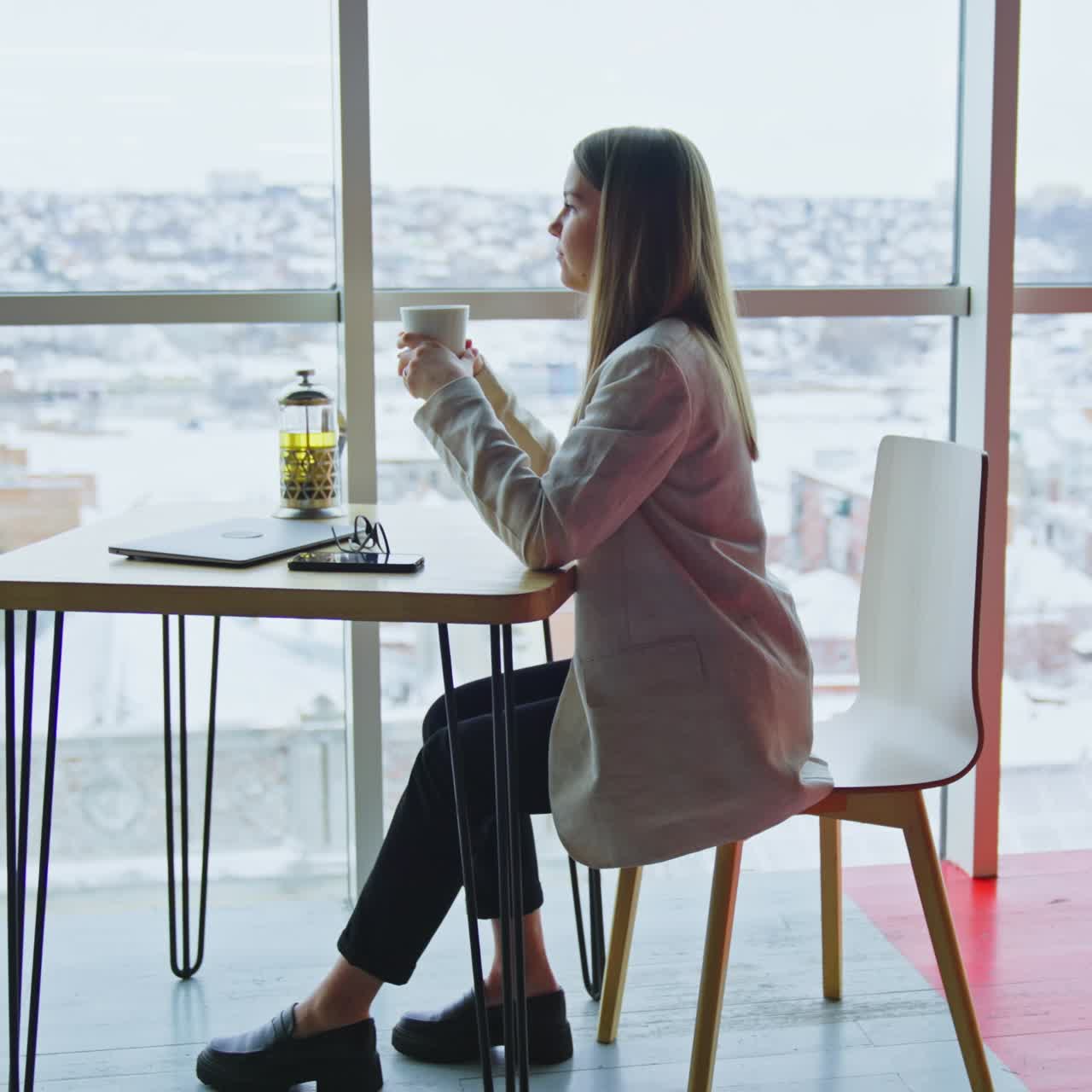 Confident happy woman sitting at table and having tea. Beautiful woman enjoying lunch break time at work. Side view