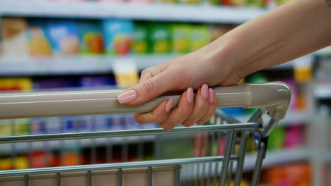 a hand pushing a shopping cart in a supermarket