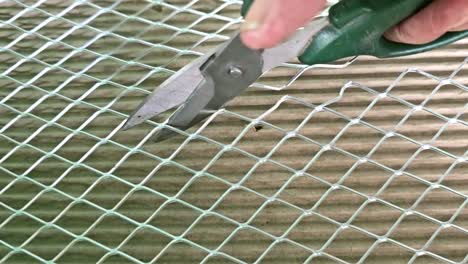 close up shot of someone cutting a metal screen