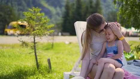 Close-up-Travelling-Mom-and-daughter-are-sitting-on-the-beach-near-the-bushes