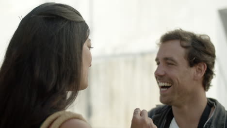 closeup of happy couple talking outside, laughing and kissing.