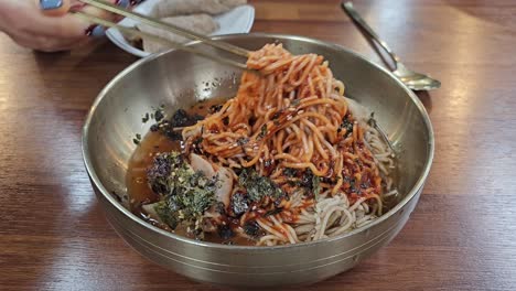 Chopsticks Mixing Korean Buckweet Cold Noodle Soup in Metal Bowl - Close-up