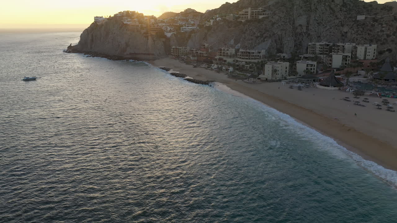 tiro de drone de resorts en playa el médano con montañas en la distancia en cabo san lucas mexico, comenzando en el océano y luego revelando los edificios