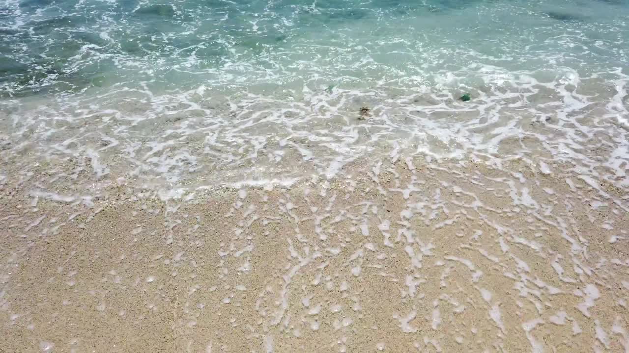 섬의 열대 모래 해변을 향해 굴러다니는 은 파란 바물 물의 파도와 여름에 파동하는 바다 표면을 쳐다보는 태양의 반이는 불꽃.