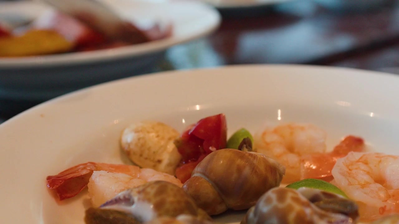 Primo piano di pinze che servono frutti di mare su un piatto bianco a un buffet di ristorante.
