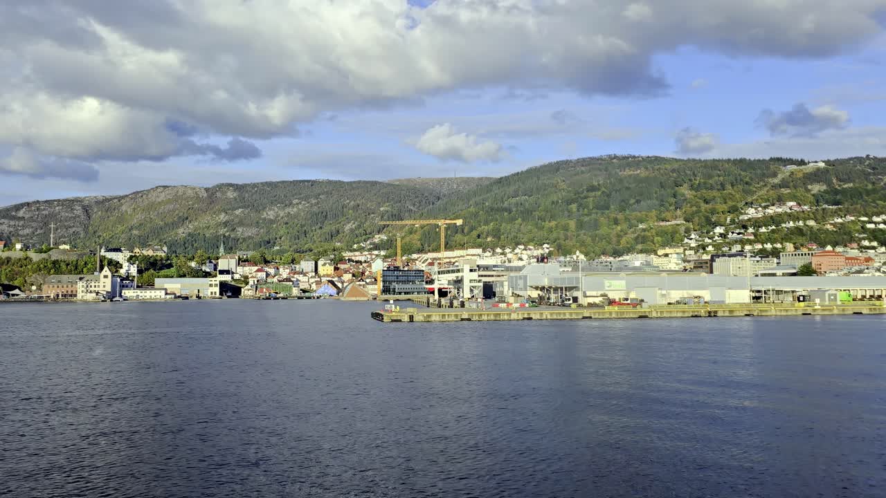 Side view from sea showing Bergen city, Nordnes and Sandviken as vessel departs in summer sunlight